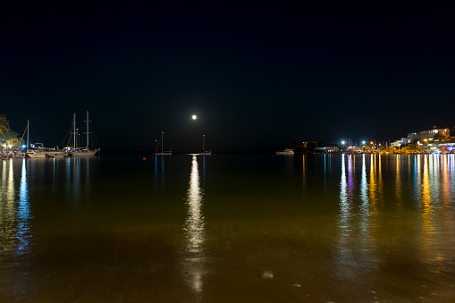 Lights and the moon reflect on the evening waters of Lake Hamilton near Hot Springs, Arkansas.