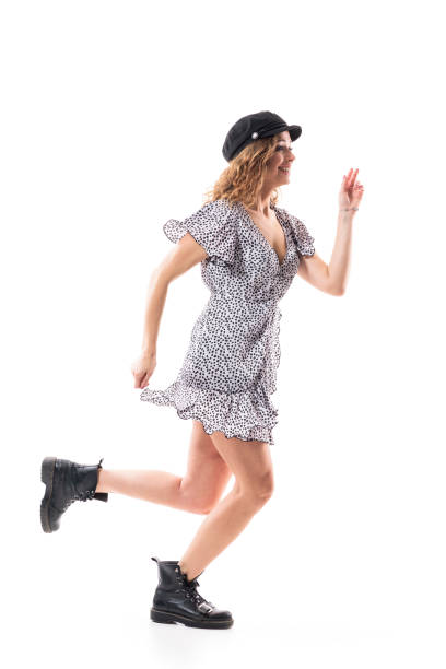 揺れる揺れるドレスを着て走る興奮した幸せな熱狂的な若い女性。サイドビュー。 - フラウンスドドレス ストックフォトと画像