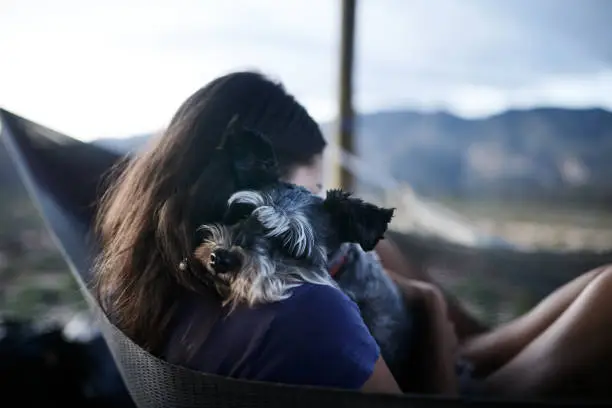Shot of a young woman relaxing with her adorable dog in a hammock