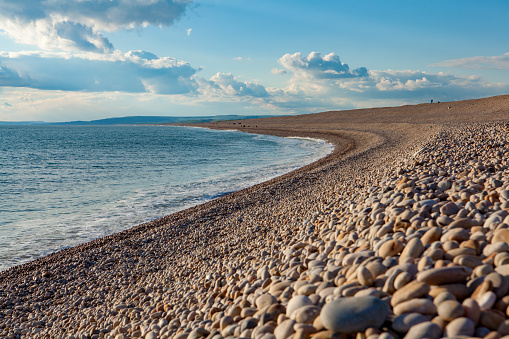 Chesil Beach in Dorset, southern England is one of three major shingle structures in Britain. Its name is derived from the Old English ceosel or cisel, meaning \