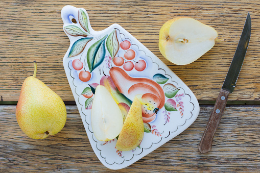 Halved ripe pear fruit and knife on a wooden table