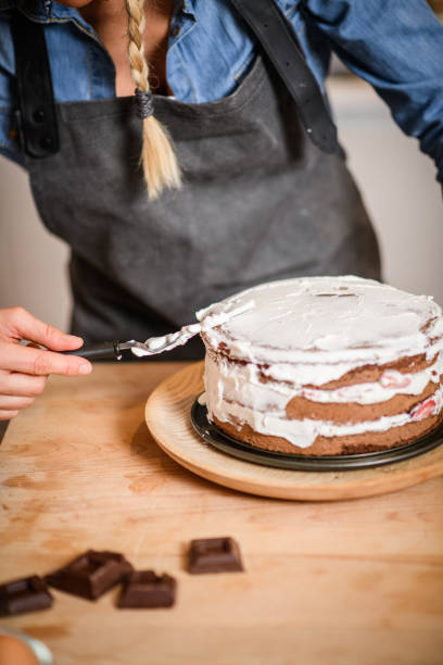 istock Woman baking at home, drip cake preparation: Spreading whipped cream 1254774345