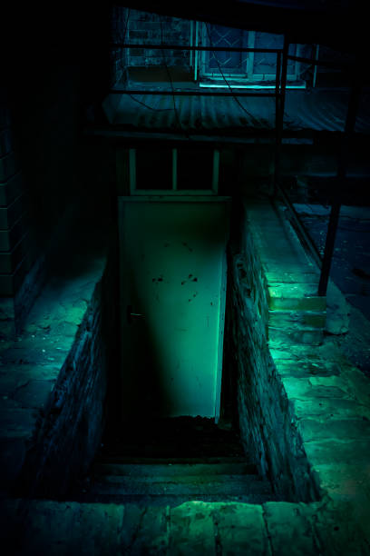 escadaria de horror místico e porta para um porão escuro em uma velha casa abandonada decrépita e assustadora com luz verde azul paranormal e terríveis sombras assustadoras causando medo - basement spooky cellar door - fotografias e filmes do acervo