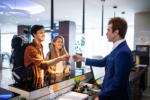 Redhead receptionist taking id card and assisting guests for checking in at luxury hotel