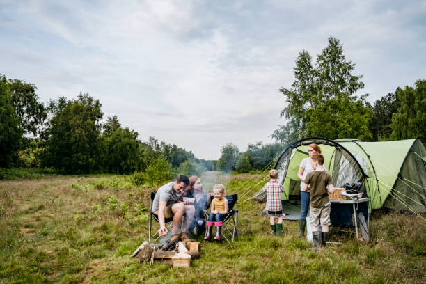 Father and mother with children on springtime camping trip Mid adult parents spending weekend time with their young children on camping trip in woodland area. camping stock pictures, royalty-free photos & images