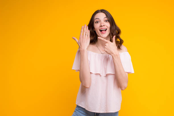 schöne aufgeregt junge brünette frau zeigt zeigen auf verlobung seherring auf ihrem finger, tragen sommer stilvolle bluse, stehen isoliert auf gelbem hintergrund. es tut mir leid, dass ich tatsächlich verheiratet bin - wedding bride buying caucasian stock-fotos und bilder