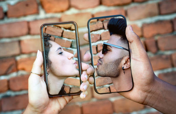 Multi-ethnic couple kissing through mobile phones Multi-ethnic couple kissing through mobile phones. Social distancing concept during coronavirus quarantine. indian couple kiss stock pictures, royalty-free photos & images