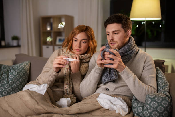 istock sick couple with thermometer and tea at home 1254779328
