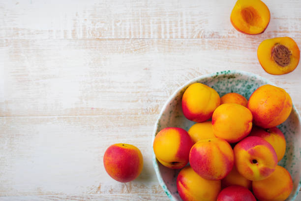 istock Fresh juicy fruit nectarines in ceramic bowl  on  white wooden background. Selective focus. Top view. Rustic style. 1254779753