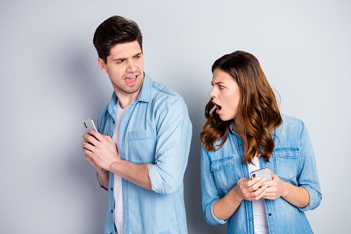 Portrait of frustrated crazy girl use smartphone see her boyfriend, chatting with cute woman she scream he hide device wear casual fashion jeans isolated over gray color background