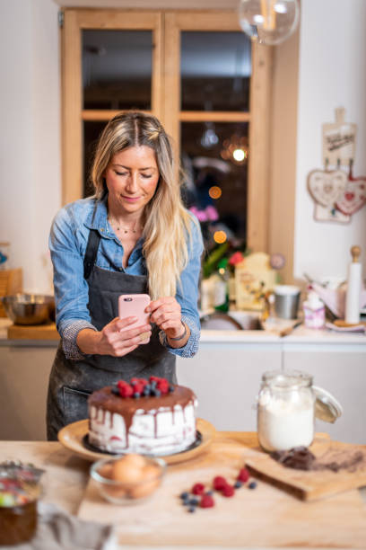 istock Woman baking at home: Photographing her drip cake with berries 1254782243