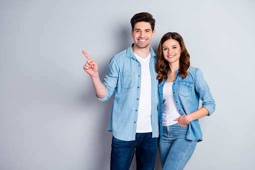 Retrato de positivo alegre pareja cónyuge punto índice dedo presente promoción de anuncio llevar ropa de estilo casual aislado sobre el fondo de color gris photo