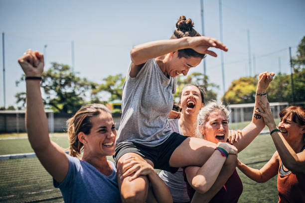Women celebrating victory outdoors on soccer field Group of women, female soccer players, celebrating victory outdoors on soccer field. football player girlfriend stock pictures, royalty-free photos & images