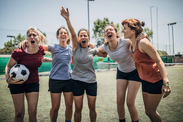Women celebrating victory on soccer field Group of women, female soccer players, celebrating victory outdoors on soccer field. football player girlfriend stock pictures, royalty-free photos & images