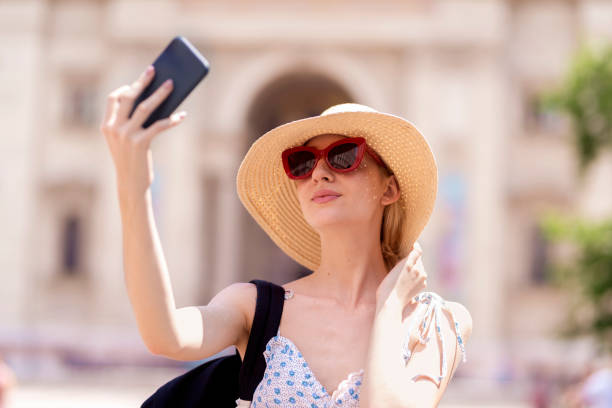 istock Attractive young woman making self portrait while standing in the city 1254786666