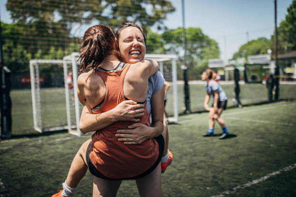 Two women huging on soccer field Group of women, female soccer players, celebrating victory outdoors on soccer field. football player girlfriend stock pictures, royalty-free photos & images