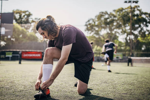 istock Men tying shoelace outdoors on soccer field 1254787787