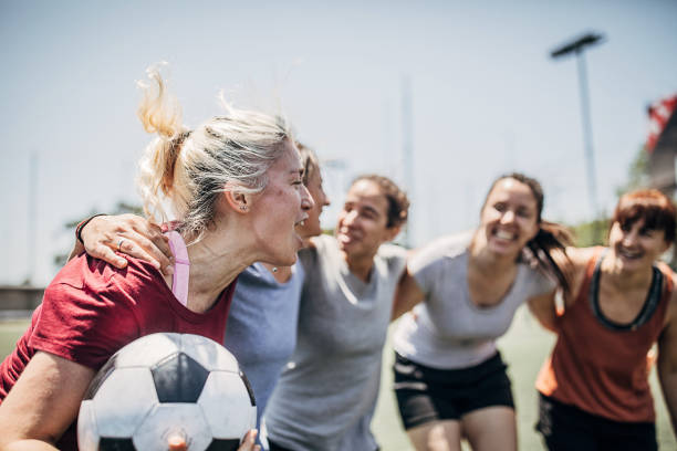 Group of women celebrating victory outdoors on soccer field Group of women, female soccer players, celebrating victory outdoors on soccer field. football player girlfriend stock pictures, royalty-free photos & images