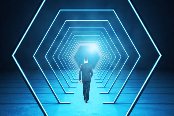istock businessman walking in modern blue interior with abstract luminous hexagon corridor. 1254794047