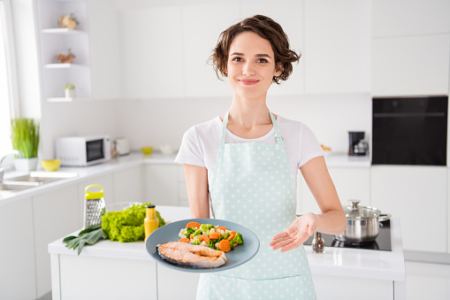 Have your gastronomy masterpiece, Photo of housewife lady chef showing, grilled salmon trout fillet steak roasted garnish cook dinner one person portion wear apron modern kitchen indoors