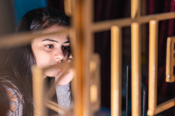 young indian woman staying isolation at home for self quarantine and looking outside from window. - facial expression child asia asian and indian ethnicities imagens e fotografias de stock