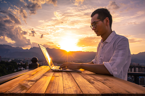Businessman working with laptop at sunset