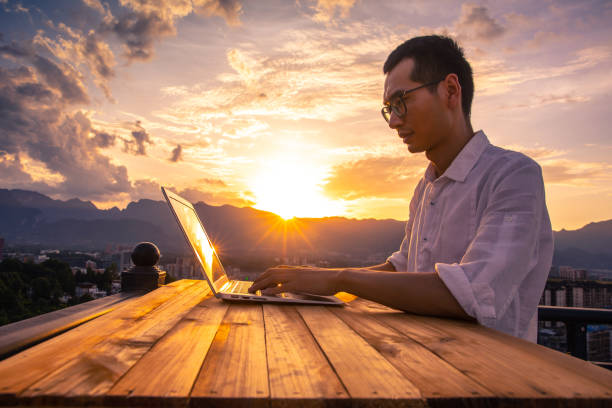 empresário trabalhando com laptop ao pôr do sol - roof men business city - fotografias e filmes do acervo