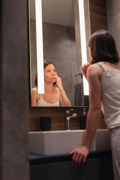 istock Woman brushing teeth in bathroom 1254797850