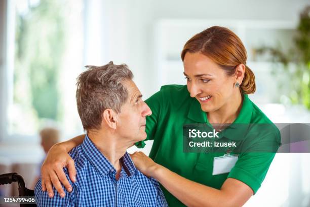 Cheerful Social Worker Supporting Senior Man Stock Photo - Download Image Now - Senior Men, Volunteer, 70-79 Years