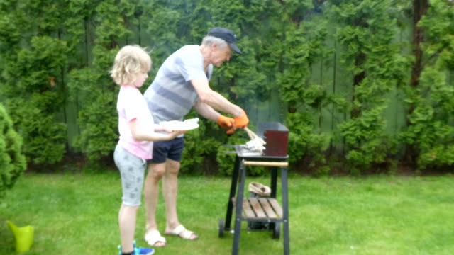 Grandfather and grandson having a barbecue.