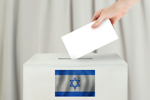 Israeli Vote concept. Voter hand holding ballot paper for election vote on polling station