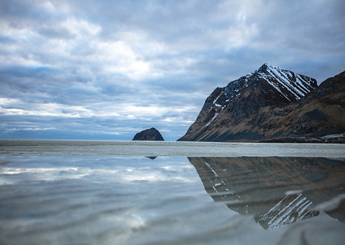 Mountain reflected in water at Haukeland beach in Lofoten.