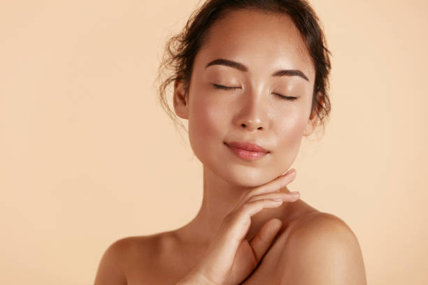 Beauty face. Woman with natural makeup and healthy skin portrait Beauty face. Woman with natural makeup and healthy skin portrait. Beautiful asian girl model touching fresh glowing hydrated facial skin on beige background closeup. Skin care concept glowing stock pictures, royalty-free photos & images