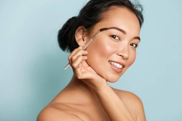 istock Beauty. Woman brushing eyebrows with makeup brush portrait 1254804564