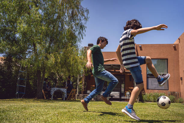 istock Playful boys playing soccer in the back yard 1254805567
