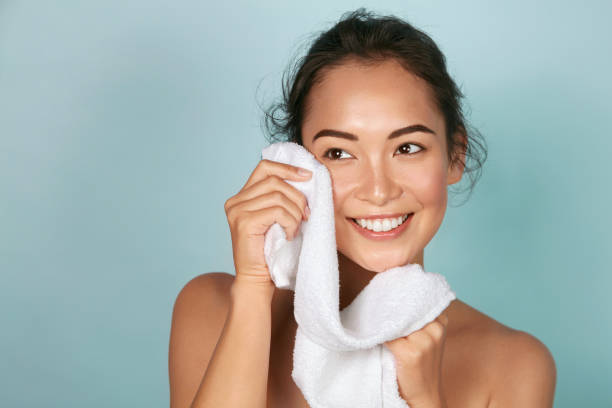 Washing face. Closeup of woman cleaning skin with towel portrait Washing face. Closeup of woman cleaning skin with towel portrait. Beautiful asian girl model wiping facial skin with soft facial towel, removing makeup. High quality studio shot woman washing face stock pictures, royalty-free photos & images