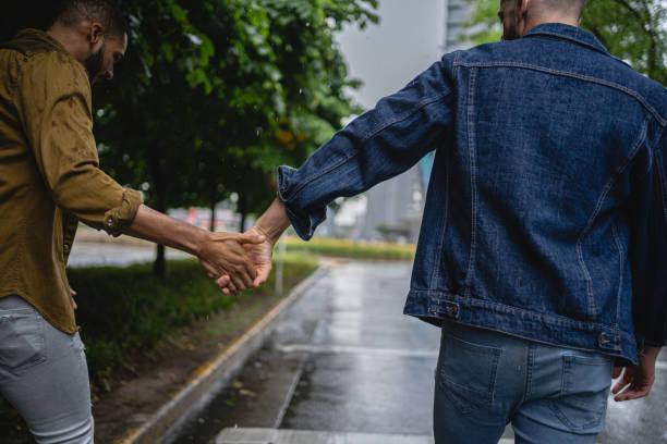 istock Gay couple holding hands while walking during a rainy day 1254805737