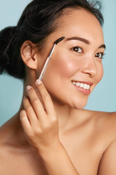 istock Makeup. Woman brushing brows with eyebrow brush closeup portrait 1254806590