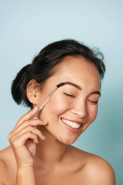 istock Beauty. Woman brushing eyebrows with makeup brush portrait 1254806620