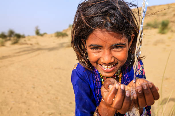 indische kleine mädchen trinken frisches wasser, wüstendorf, rajasthan, indien - poverty india child little girls stock-fotos und bilder