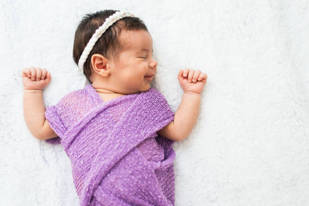 Close-up of a newborn baby girl peacefully sleeping in the crib. High angle view.