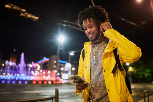 Black man playing music on his phone while walking outdoors