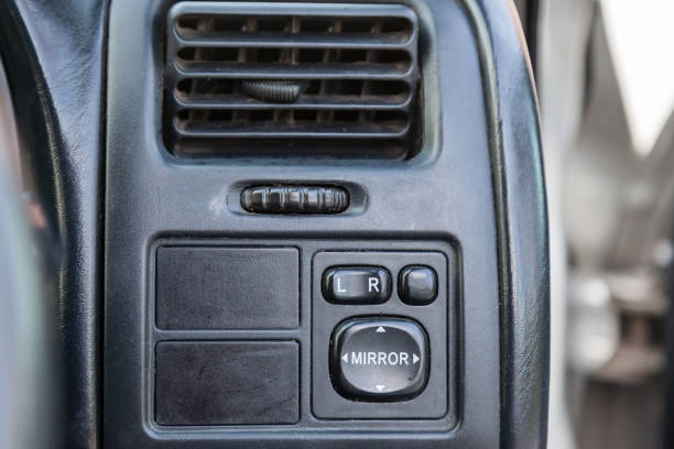 istock Close-up of a black plastic panel with buttons for automatically adjusting side mirrors with white markings under the air conditioning grille with air direction correction. 1254810721