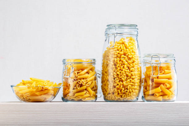 istock Different pasta types in large glass jars and bowl on wooden table. 1254813494