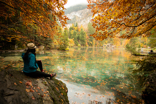 Asian woman  enjoying the view of turquoise lake Blausee in Swiss Alps