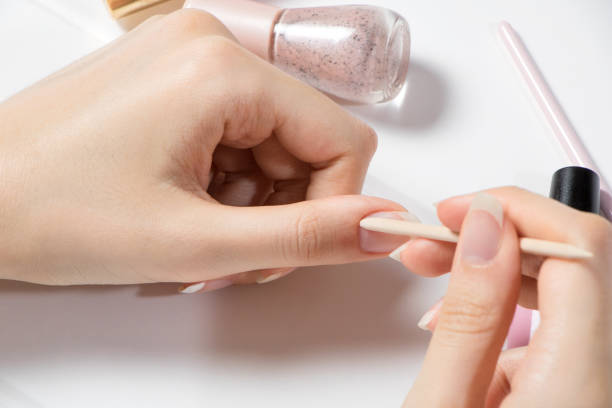 Manicure. Push back the cuticle with a wooden stick. A woman does her own manicure. Home nail care. Beauty wellness spa treatment concept. Skin care, hygiene. Preparing nails before manicure. manicura. empuje hacia atrás la cutícula con un palo de madera. una mujer hace su propia manicura. cuidado de uñas en casa. concepto de tratamiento de spa de bienestar de belleza. cuidado de la piel, higiene. preparar las uñas antes de la manicura.