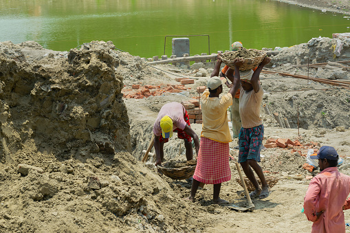 Howrah, West Bengal, India - 7th May 2017 : Indian male workers digging and carrying out soil at buliding construction site. India has a huge population of daily wage earners.