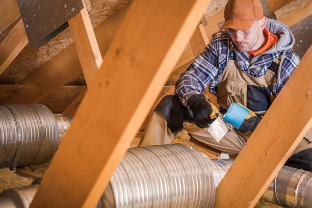 Male Contractor Binding Ventilation Pipes With Duct Tape. Construction Worker Wrapping HVAC Air Duct With Silver And Blue Foil Tape In Attic Of Residential Building. air duct photos stock pictures, royalty-free photos & images
