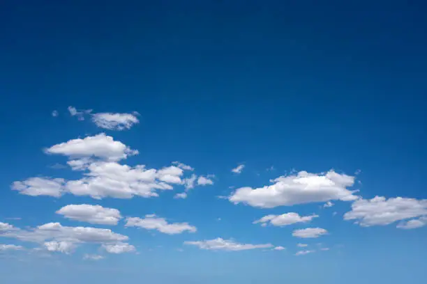 Blue summer sky with cumulus clouds in white as a background