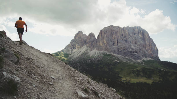 camino de hombre corriendo en la montaña: aventuras al aire libre en los dolomitas - sella pass fotografías e imágenes de stock